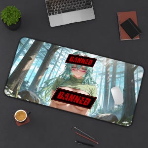 Peut inclure: Tapis de souris rectangulaire avec une illustration de style anime d'une femme aux cheveux verts et un fond de forêt. L'image est partiellement obscurcie par des tampons rouges "BANNED". Une souris d'ordinateur, un ordinateur portable et d'autres fournitures de bureau sont visibles.