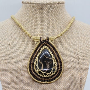 May include: A brown and tan macrame necklace with a black and brown agate pendant.