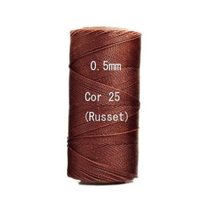 May include: A spool of russet-colored cord, 0.5mm in diameter, labeled "Cor 25." The tightly wound cord is a rich, dark brown color, suitable for various crafting projects. The spool is set against a plain white background.