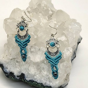 May include: A pair of turquoise and silver dangle earrings with a beaded accent. The earrings feature a turquoise stone and intricate silver details.