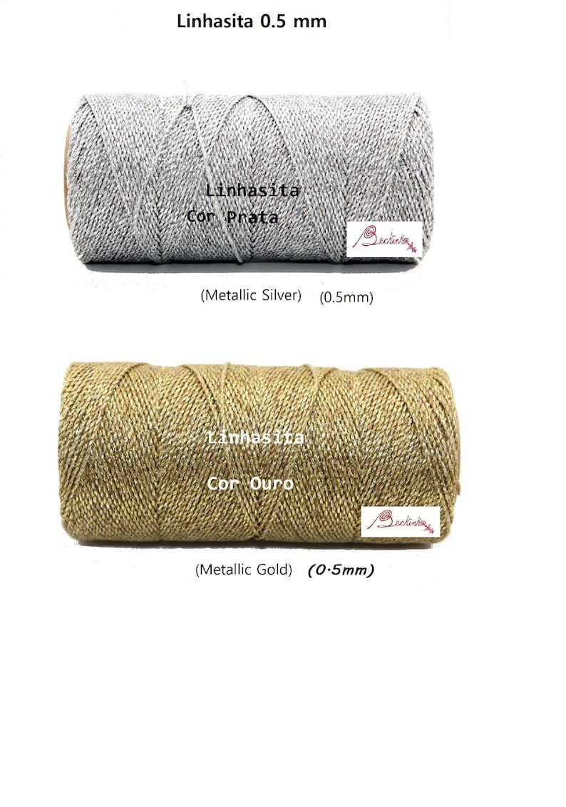 May include: Two spools of metallic thread, one silver and one gold. The spools are labeled "Linhasita Cor Prata" and "Linhasita Cor Ouro". Both spools are 0.5 mm thick.
