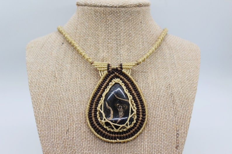 May include: A brown and tan macrame necklace with a black and brown agate pendant.