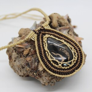 May include: A brown and beige macrame necklace with a black and gold agate pendant.