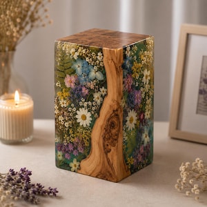 Op de afbeelding: Een rechthoekig blok van heldere hars en natuurlijk hout, met een verticale strook lichtbruine houtnerf geflankeerd door ingebedde gedroogde bloemen in tinten wit, blauw, roze, geel en paars, gecombineerd met groen varenblad.