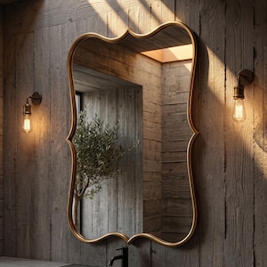 May include: A wall-mounted mirror featuring a gold-toned frame with a distinctively curved, scalloped silhouette. The reflective glass surface is encased in a smooth, metallic border that follows the undulating shape of the mirror's edges.