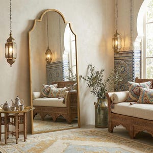 Puede incluir: Un gran espejo de pie con marco dorado y parte superior arqueada. La habitaci&oacute;n cuenta con faroles ornamentados, muebles de madera tallada, cojines decorativos y una alfombra estampada, creando un interior bohemio.