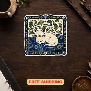May include: A square sticker featuring a cream-colored cat resting on a blue patterned quilt. Above the cat is a potted plant with green leaves. The entire scene is enclosed in a dark blue decorative border with small flowers and hearts.