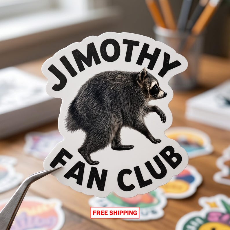 May include: A die-cut sticker featuring a realistic illustration of a grey and black raccoon in the center. The text JIMOTHY FAN CLUB is printed in bold black capital letters, arching over the top and curving along the bottom of the sticker.