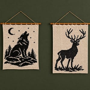 May include: Two wall hangings with nature-themed designs. One features a black wolf howling at the moon and stars, the other a black deer with large antlers. Both are made of woven fabric and suspended from wooden dowels.