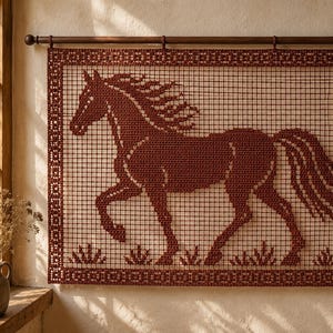 May include: A rectangular dark red crochet wall hanging featuring a detailed horse silhouette in a grid pattern. The piece is framed by a decorative border and suspended from a dark wooden rod, showcasing intricate needlework and texture.