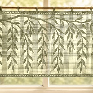 May include: A rectangular sage green crochet curtain featuring a detailed willow branch pattern with hanging leaves. The curtain is constructed with a grid-like filet crochet technique and is suspended from a wooden rod by small fabric loops.