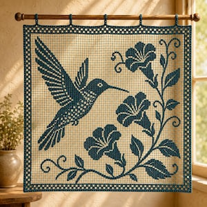 May include: A square crochet wall hanging featuring a dark teal hummingbird in flight towards three trumpet-shaped flowers on a vine. The piece is crafted with a grid-like pattern and is suspended from a horizontal wooden rod with five loops.