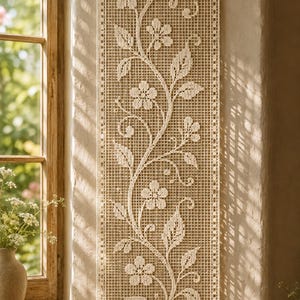 Puede incluir: Un tapiz de pared rectangular y largo de ganchillo color crema con un intrincado patrón de rejilla abierta. El diseño muestra un motivo central de enredadera con flores detalladas de cinco pétalos y hojas puntiagudas, suspendido de una fina varilla de madera.