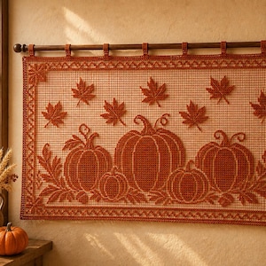 May include: A rectangular crochet wall hanging featuring a burnt orange pumpkin and maple leaf pattern on a light beige grid background, suspended from a dark wooden rod with six fabric loops along the top edge and a decorative border.