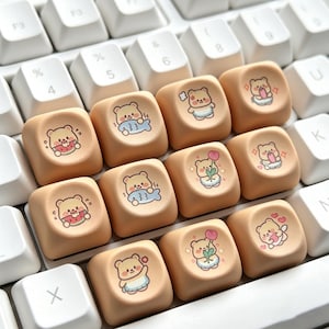 May include: A close-up of a computer keyboard with custom keycaps. The keycaps are a light peach color and feature cute cartoon bear illustrations. The bears are depicted with various accessories and expressions, adding a playful touch to the keyboard.