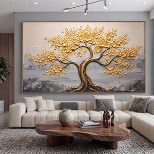 May include: A large rectangular wall art piece featuring a textured, three-dimensional tree with a metallic gold trunk and golden leaves. The background consists of abstract, layered brushstrokes in shades of gray, white, and cream, creating a sense of depth and movement behind the prominent, raised golden tree structure.