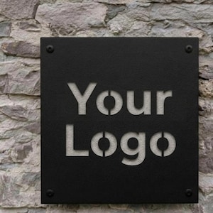 May include: A black square sign with the words "Your Logo" cut out in a stencil font. The sign is mounted on a stone wall with four visible screws in each corner.