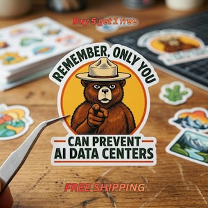 May include: A die-cut vinyl sticker featuring a brown bear wearing a tan ranger hat, pointing forward. The text reads: REMEMBER, ONLY YOU CAN PREVENT AI DATA CENTERS. The design is set against a circular yellow background with a dark orange border.