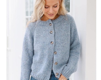 May include: A light blue cardigan sweater with a round neckline and button-up closure. The sweater has long sleeves and is made of a soft, textured knit fabric. The buttons are a light brown color. The sweater is worn with blue jeans.