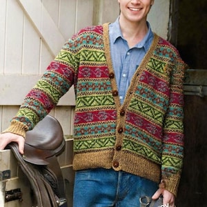 May include: A multi-colored cardigan sweater with a V-neck and button closure. The sweater features a pattern of green, red, and blue geometric designs. The cuffs and trim are a solid brown color. The person is wearing blue jeans and a blue button-down shirt.