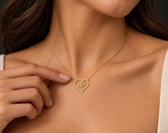 Pode incluir: Um colar de tom dourado com um pingente delicado em forma de coração. O pingente incorpora a silhueta de uma cabeça de cavalo e inclui o nome Charlie escrito em letra cursiva dentro da moldura do coração numa corrente fina.