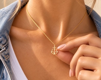 Pode incluir: Um colar de tom dourado com uma corrente delicada e um pequeno pingente em forma de âncora combinada com um coração. O pingente está suspenso no centro da corrente, que repousa sobre o pescoço. O metal possui um acabamento polido.