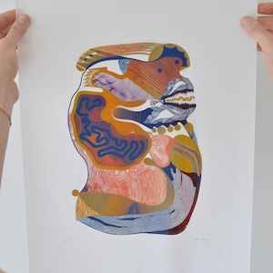 May include: Abstract art print featuring a colorful, organic form. The artwork uses a palette of orange, blue, yellow, and red, with intricate line work and patterns. The print is held by two hands against a white background.