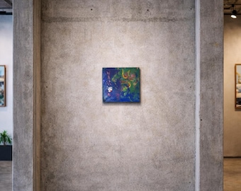 May include: A small, square abstract painting with a dark blue background and splashes of green, yellow, and red. The artwork is mounted on a concrete wall in a modern gallery setting. The painting's colours create a vibrant contrast.
