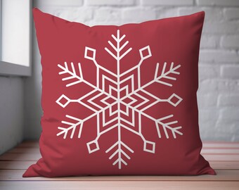 May include: A red throw pillow with a white snowflake design. The snowflake is a simple geometric design with six points.
