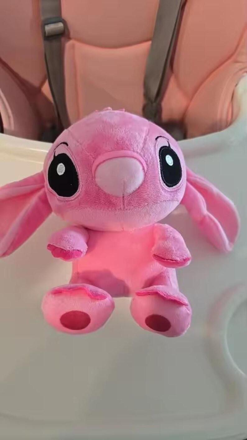 Puede incluir: Un peluche rosa con un personaje de orejas grandes, ojos negros y nariz redonda. El juguete tiene una textura suave y difusa y est&aacute; sobre una superficie blanca. Tambi&eacute;n son visibles los brazos y los pies del juguete.