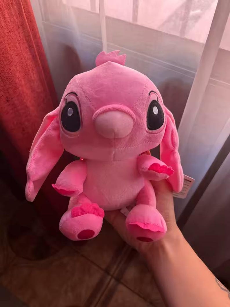 Puede incluir: Un peluche rosa de un personaje de dibujos animados con grandes ojos negros, orejas largas y una peque&ntilde;a antena. El juguete tiene una textura suave y difusa.