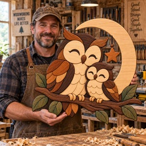 Könnte beinhalten: Ein Wandbild aus Holz, das eine große Eule und eine kleine Eule auf einem Ast vor einer Mondsichel mit einem hängenden Stern zeigt. Die Eulen sind aus verschiedenen Braun- und Cremetönen gefertigt und mit grünen Blättern am Ast verziert.