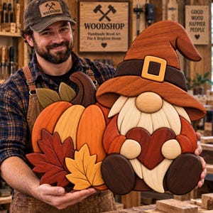 Könnte beinhalten: Ein Wandbild aus Holz, das einen Wichtel mit braunem Hut und gelber Schnalle zeigt, der ein dunkelrotes Herz hält, neben einem orangefarbenen Kürbis und zwei herbstlichen Blättern in Rot- und Gelbtönen, gefertigt aus geschichtetem Holz.