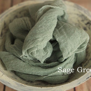 May include: Sage green fabric in a white bowl. The fabric is soft and wrinkled, and the bowl has a distressed finish.