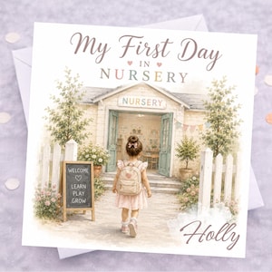 May include: A square greeting card featuring a watercolour illustration of a child with a backpack walking towards a nursery building. The text reads My First Day In Nursery, Welcome Learn Play Grow, and the name Holly in a script font at the bottom.