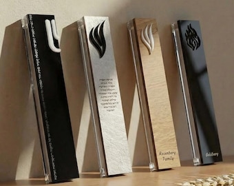 May include: Four decorative mezuzah cases in black, silver, wood, and black. Each case features a unique design, including a flame and text. The cases are displayed on a wooden shelf with a wheat stalk.