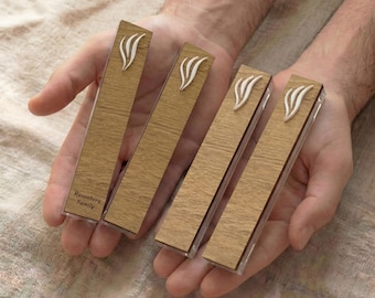 May include: Four rectangular wooden boxes with a light wood grain pattern are held in open hands. Each box has a white, stylized flame design and a clear plastic front. The text "Rosenberg Family" is printed on one box.
