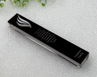 May include: A black mezuzah case with a white flame design and Hebrew text. The case has a clear, rectangular body and the words "Friedman Family" are printed on the bottom.
