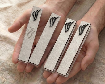 May include: Four rectangular bookmarks with a textured, light gray surface and a black, stylized flame design. One bookmark has text in a foreign language. The bookmarks are held in open hands.