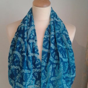 May include: A blue and white patterned scarf made of velvet. The scarf is folded in half and draped over a mannequin's neck.