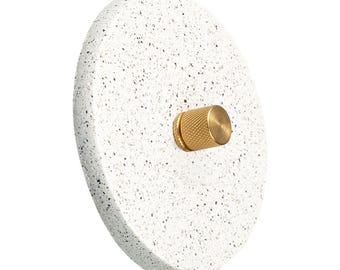 Interruttore dimmer rotativo rotondo, placca a muro in composito di pietra, pomello in ottone, arredamento minimalista.