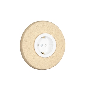 Op de afbeelding: Een ronde, beige stopcontact met een wit midden en drie gaten. Het stopcontact is geplaatst in een getextureerd, cirkelvormig frame. Het ontwerp is eenvoudig en modern, geschikt voor interieurdecoratie.