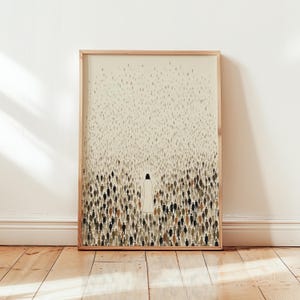 May include: A framed art print with a minimalist illustration. A figure in a white robe stands out against a crowd of people in shades of black, brown, and grey. The background is a light beige colour, and the frame is made of light wood.