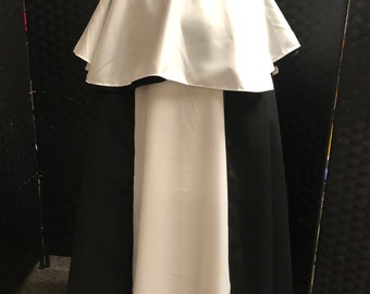May include: A white and black hooded robe with a long, flowing skirt. The robe has a large, white hood and a black collar.