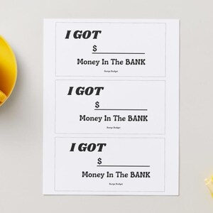 以下が含まれることがあります： 「I GOT $ Money In The BANK」の黒い文字が書かれた3枚の白いカード。 黄色のティーカップとソーサーが左上にあり、黄色の皿とペンが右下にあります。 背景は明るいグレーです。