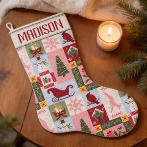 以下が含まれることがあります： 上部に「MADISON」と刺繍されたクリスマスストッキング。雪だるま、カーディナル、クリスマスツリー、そりなどのお祝いのモチーフがパッチワークデザインになっています。カラーパレットには、赤、緑、ピンク、青が含まれています。