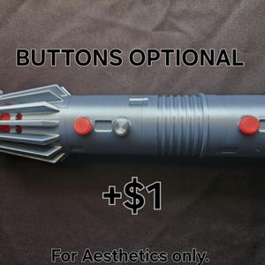 Pu&ograve; includere: Un'elica di spada laser argentata con bottoni rossi e argentati. Il testo "BUTTONS OPTIONAL" &egrave; sopra la spada laser e "For Aesthetics only." sotto. La spada laser ha un corpo cilindrico con un'impugnatura dettagliata.