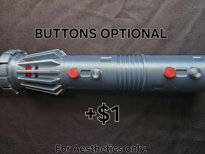 Pu&ograve; includere: Un'elica di spada laser argentata con bottoni rossi e argentati. Il testo "BUTTONS OPTIONAL" &egrave; sopra la spada laser e "For Aesthetics only." sotto. La spada laser ha un corpo cilindrico con un'impugnatura dettagliata.