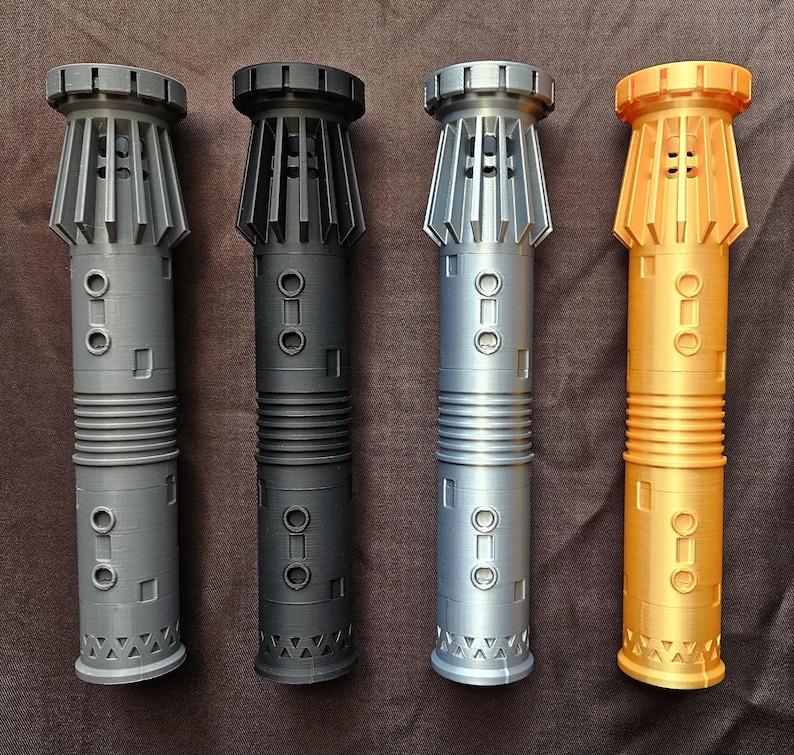 Pu&ograve; includere: Quattro repliche di spade laser in grigio, nero, argento e oro. Ognuna ha un corpo cilindrico con un'impugnatura a coste, dettagli rettangolari e circolari e una parte superiore svasata con lamelle verticali. La spada laser dorata ha un design superiore leggermente diverso.