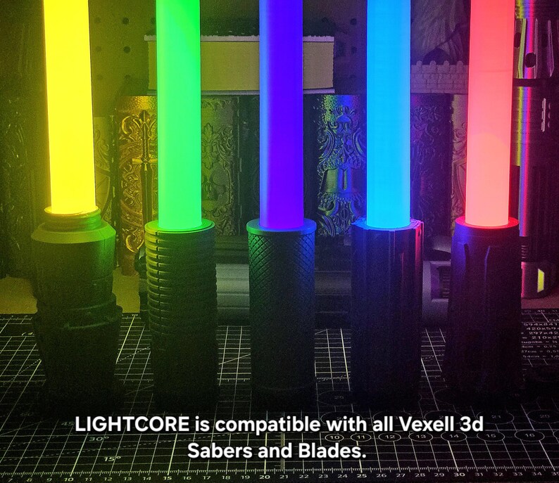 May include: Five cylindrical light sabers with glowing yellow, green, purple, blue, and red blades attached to black textured handles. The text LIGHTCORE is compatible with all Vexell 3d Sabers and Blades is printed at the bottom of the image.